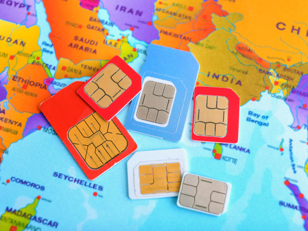A selection of SIM cards rests atop a colorful map of Asia and Africa, illustrating global connectivity and mobile communication.